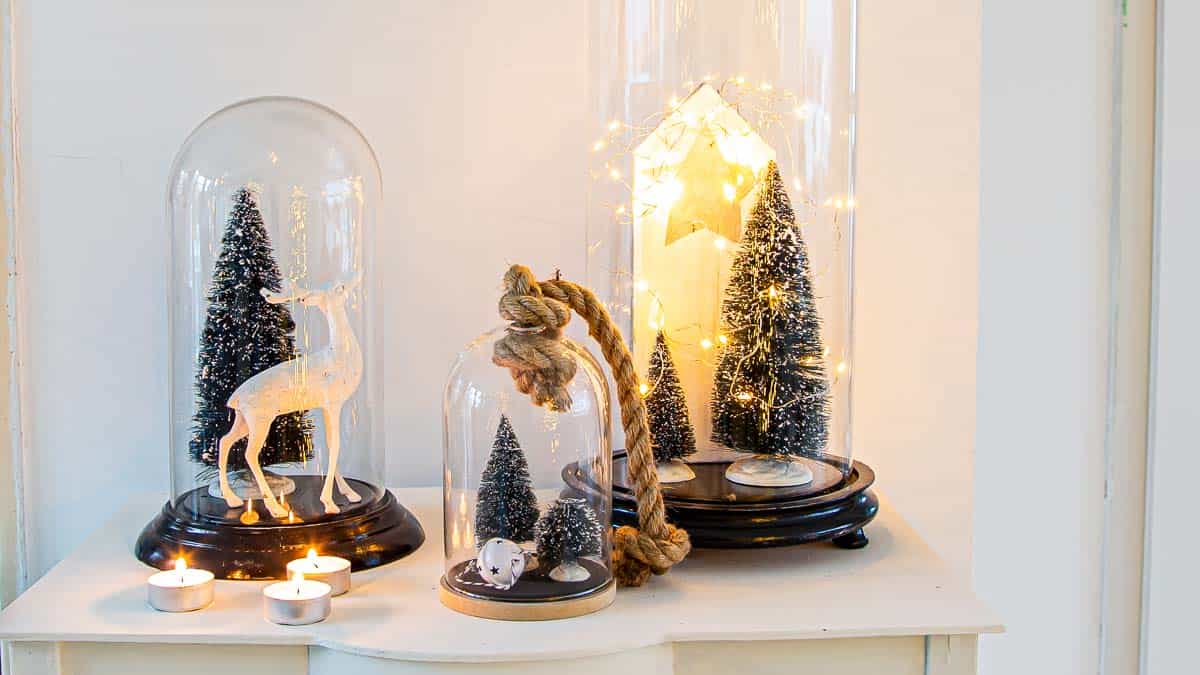 Christmas vignette with three glass cloches on a sidetable.