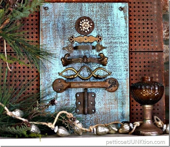 Blue painted wood plaque decorated with vintage hardware in the shape of a Christmas tree.
