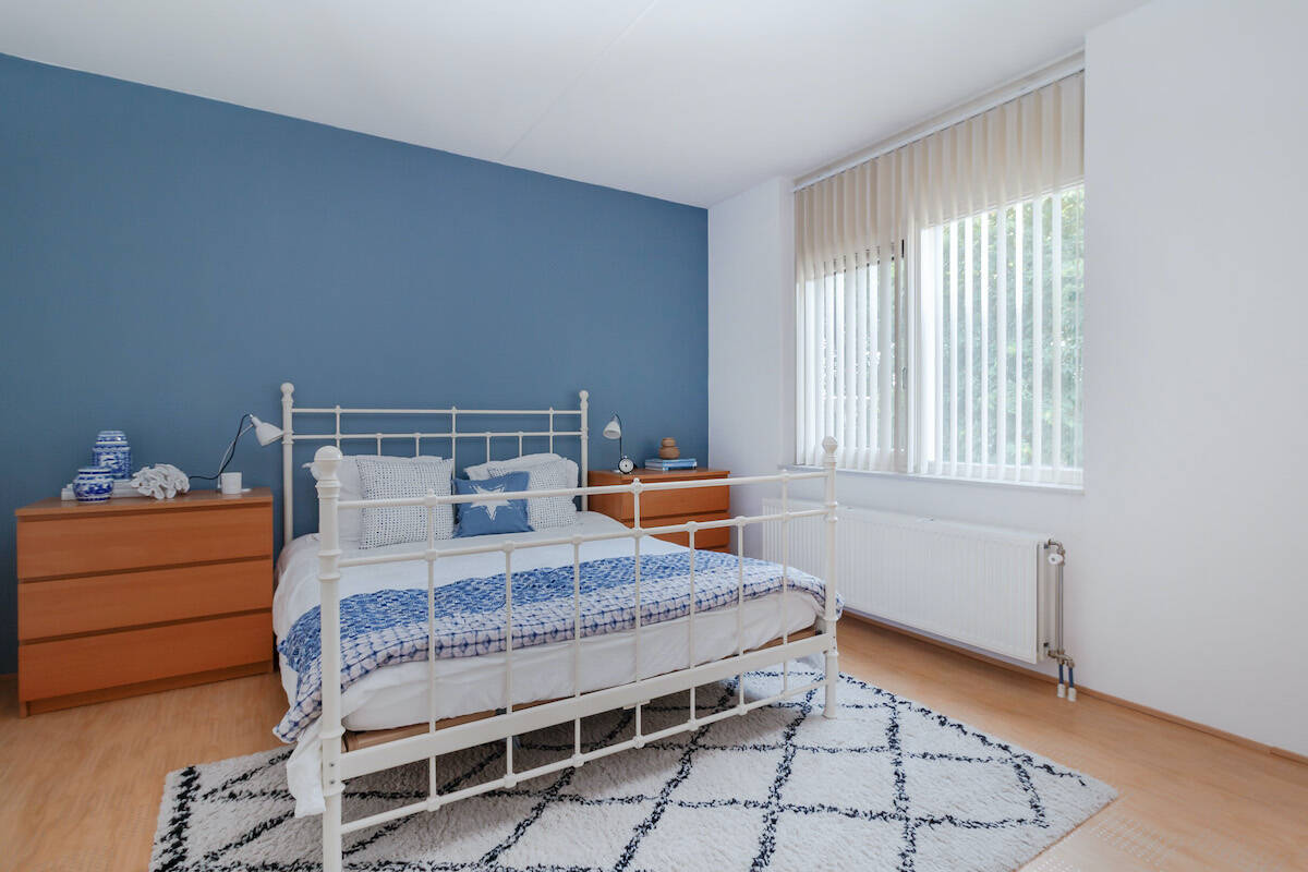 Bedroom in blue and white with a large empty blue wall in the background.