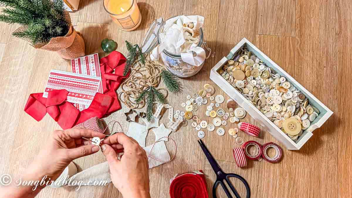 Women's hands over a craft table filled with christmas craft supplies making adult christmas crafts.