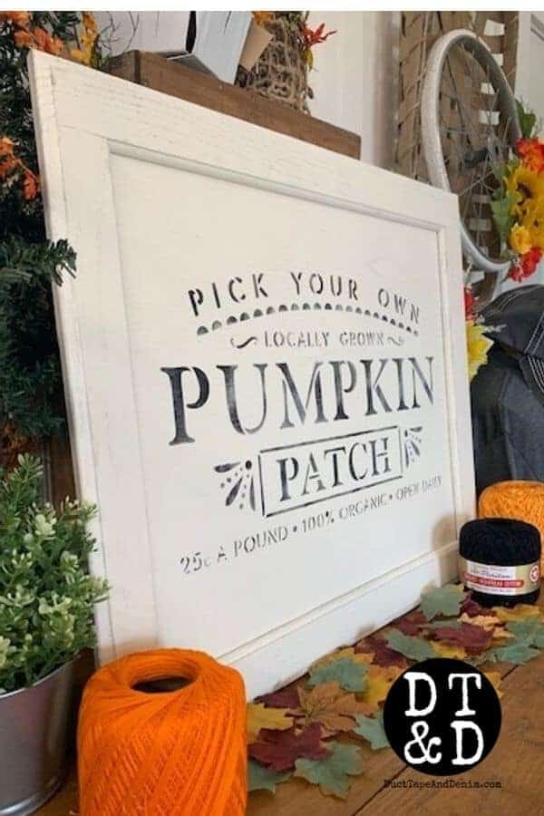 White painted cabinet door with pumpkin patch decor stenciled on top.