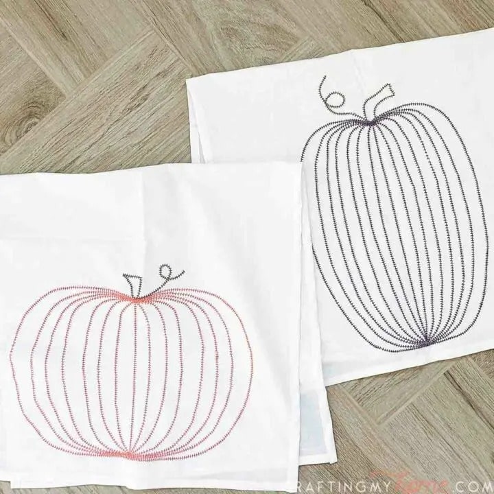 Two white tea towels with pumpkin DIY embroidery.