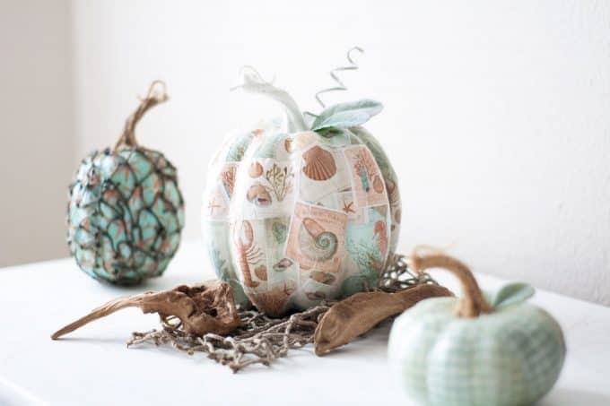 three pumpkins decoupaged with colorful scrapbook paper.
