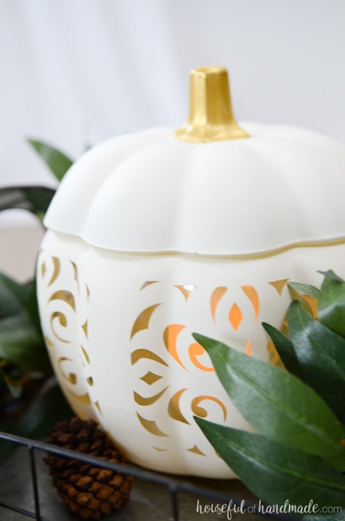 glass pumpkin painted white with cutouts in a filigree pattern.