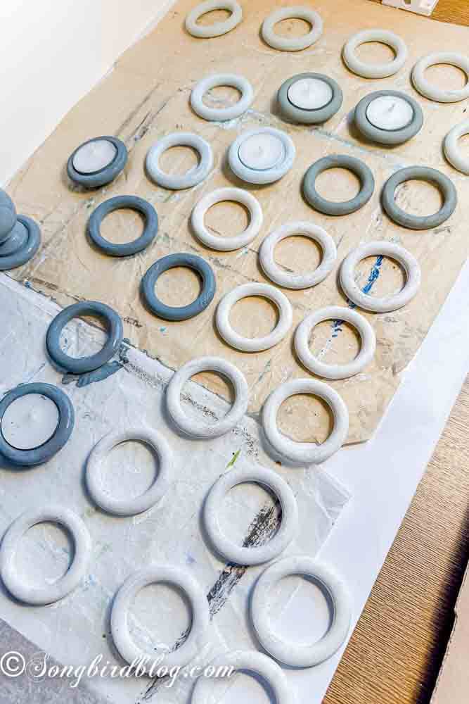 Collection of painted wood curtain rings drying on a sheet of baking paper.