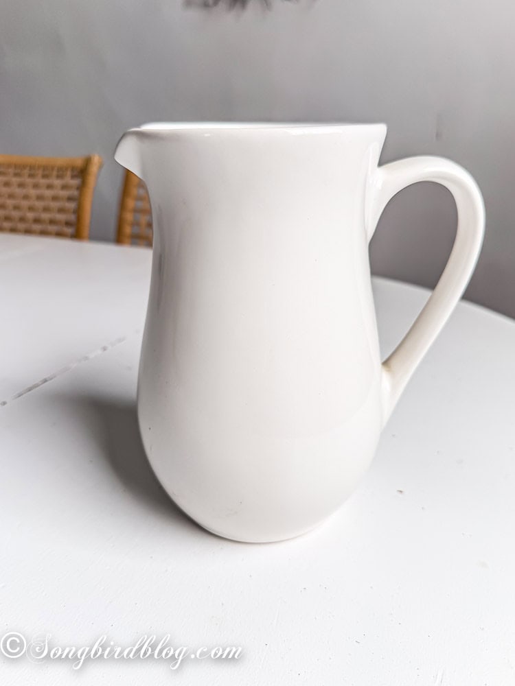 Plain white large pitcher on a white table.