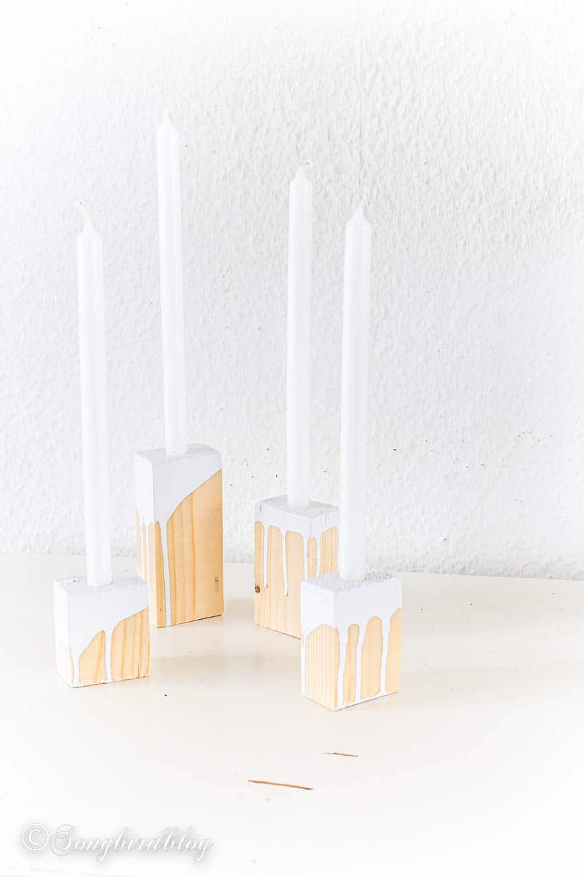unfinished wood block candle holders with taper candles and white paint dripping on the wood