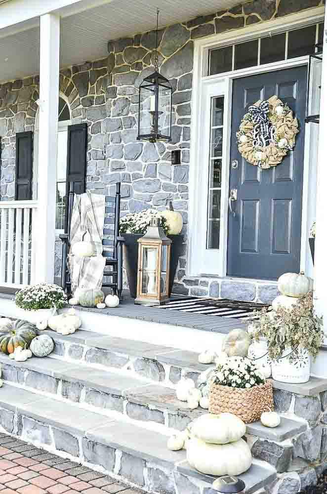 Front door with steps decorated for fall in neutral colors and with a collection of white pumpkins.