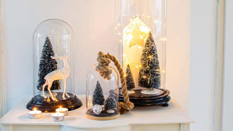 Christmas vignette with three glass cloches on a sidetable.