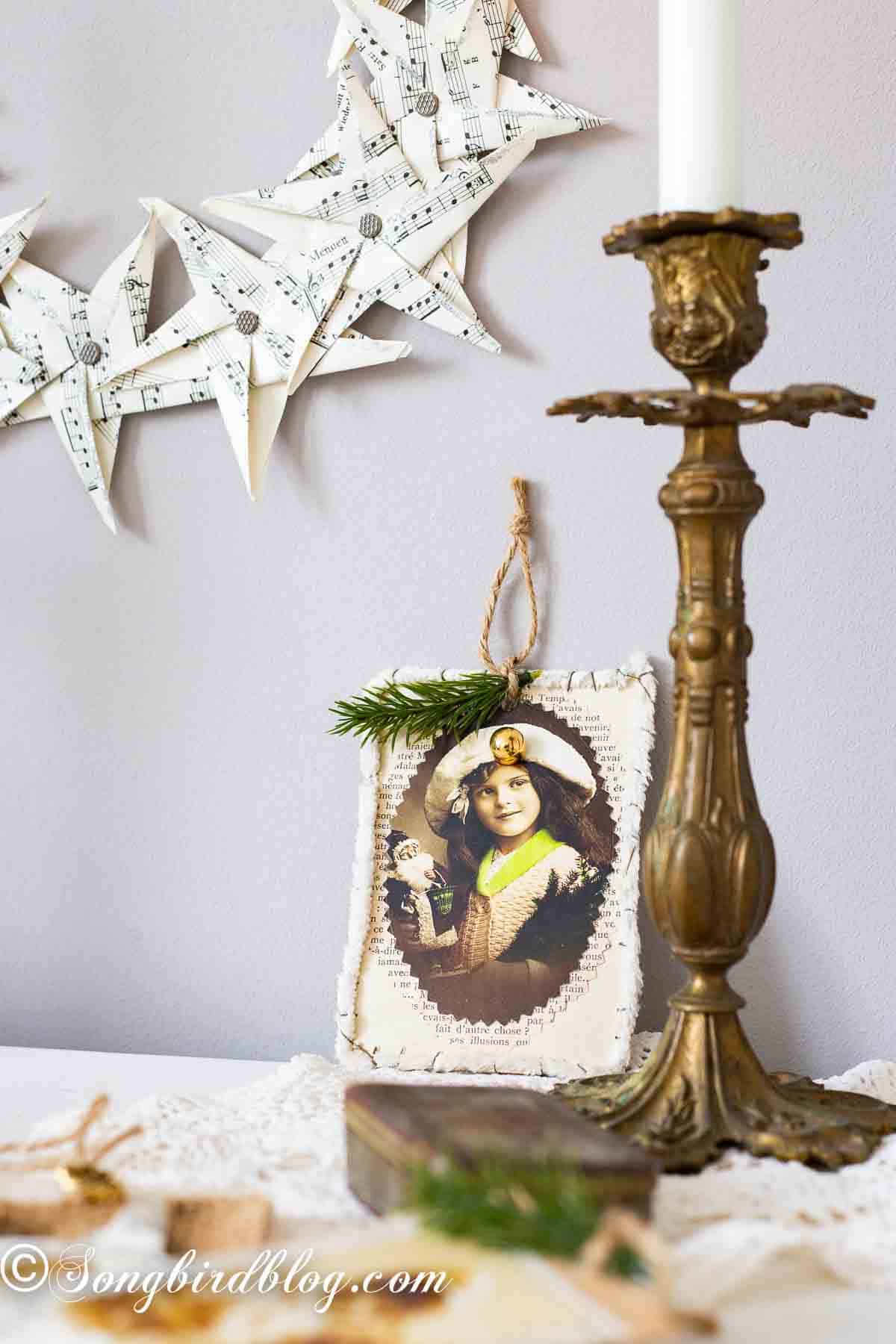 Vintage candlesticks and antique books on a layered tablecloth vignette, paper star wreath in the background on the wall.