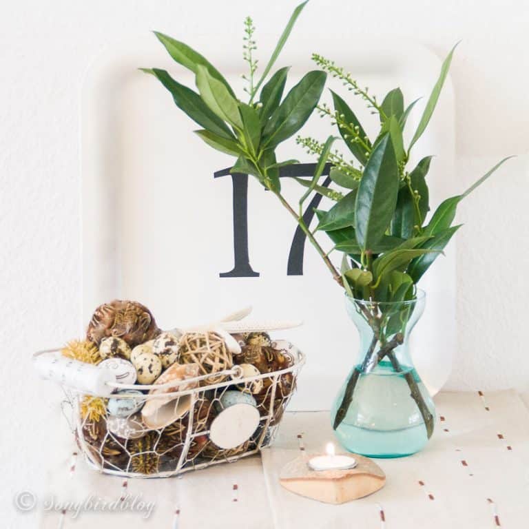 Spring decorating on a budget with green leaves in a vase and a basket with Easter decorations