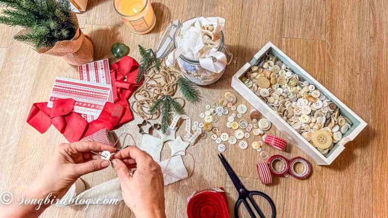Women's hands over a craft table filled with christmas craft supplies making adult christmas crafts.