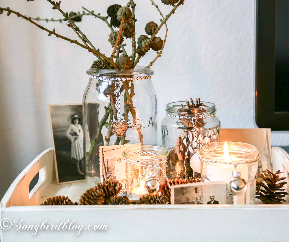 Vintage style Christmas decor on a white tray with candles and pinecone branches.