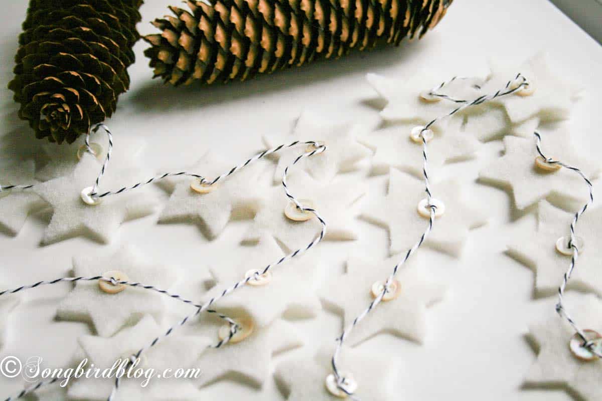 Felt star Christmas garland with vintage mother-of-pearl buttons draped across a table.