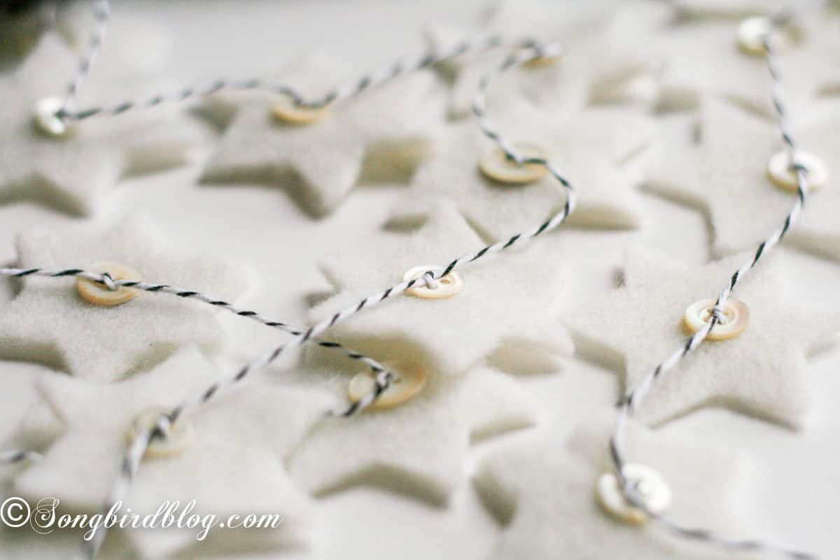 Close-up of the felt star Christmas garland showing tiny mother-of-pearl buttons on each star.