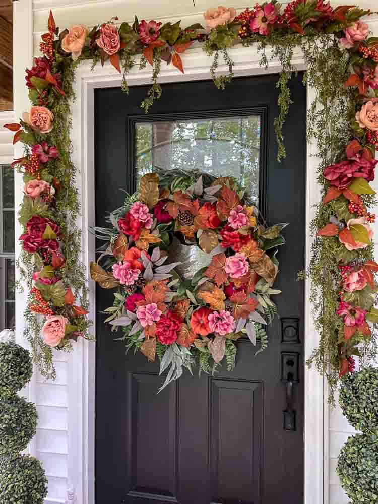 Black front door with oversized wreath in colors pink and orange.