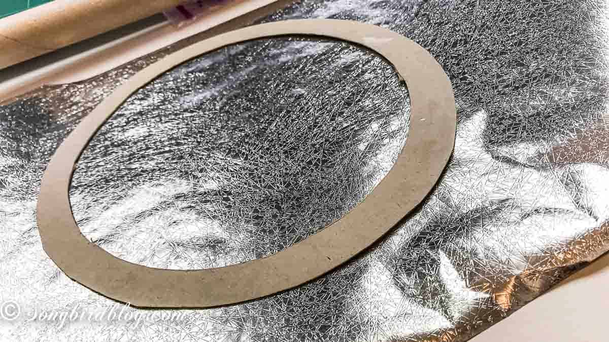 Cardboard wreath base on silver wrapping paper.