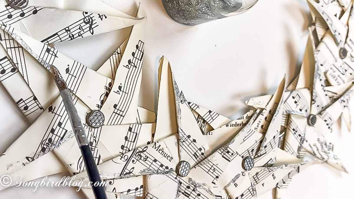 Craft brush applying glitter glue to edges of paper stars.