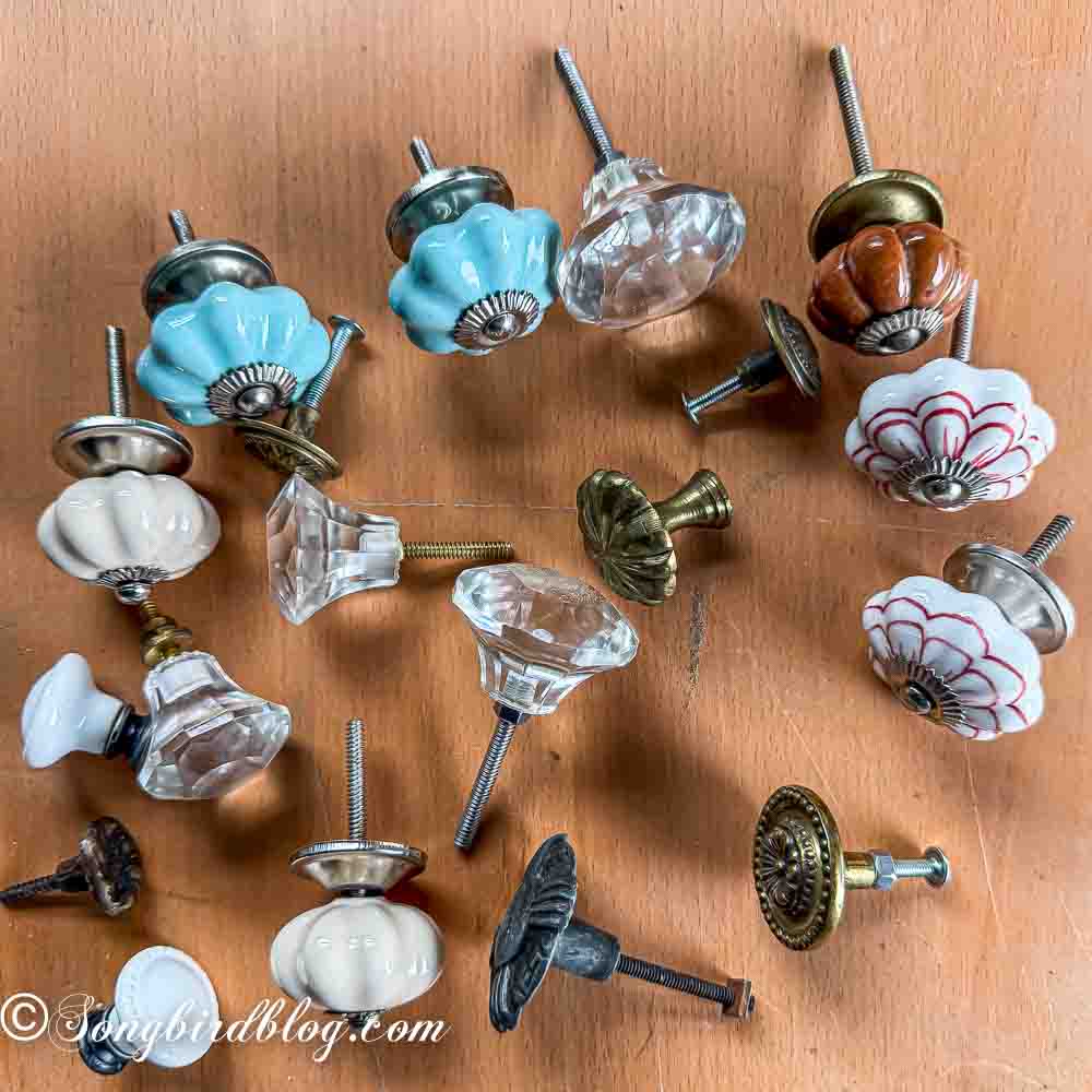 A collection of different drawer pulls laying on a wooden table.