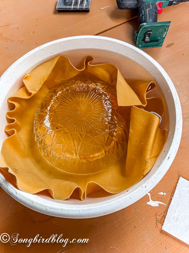 A crystal bowl inside a white bucket submerged under water.
