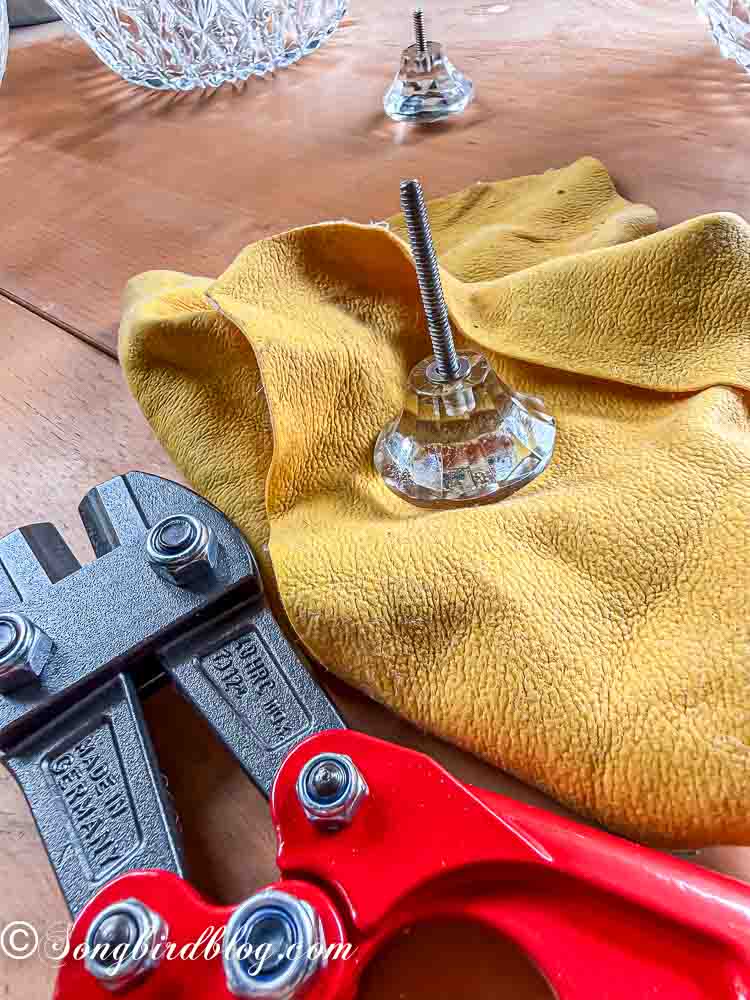 A glass drawer know with a black marking placed next to a bolt cutter.