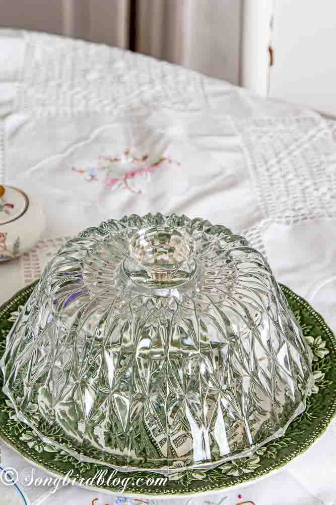 Repurposed crystal bowls into cake domes standing on a table decorated for a tea party.