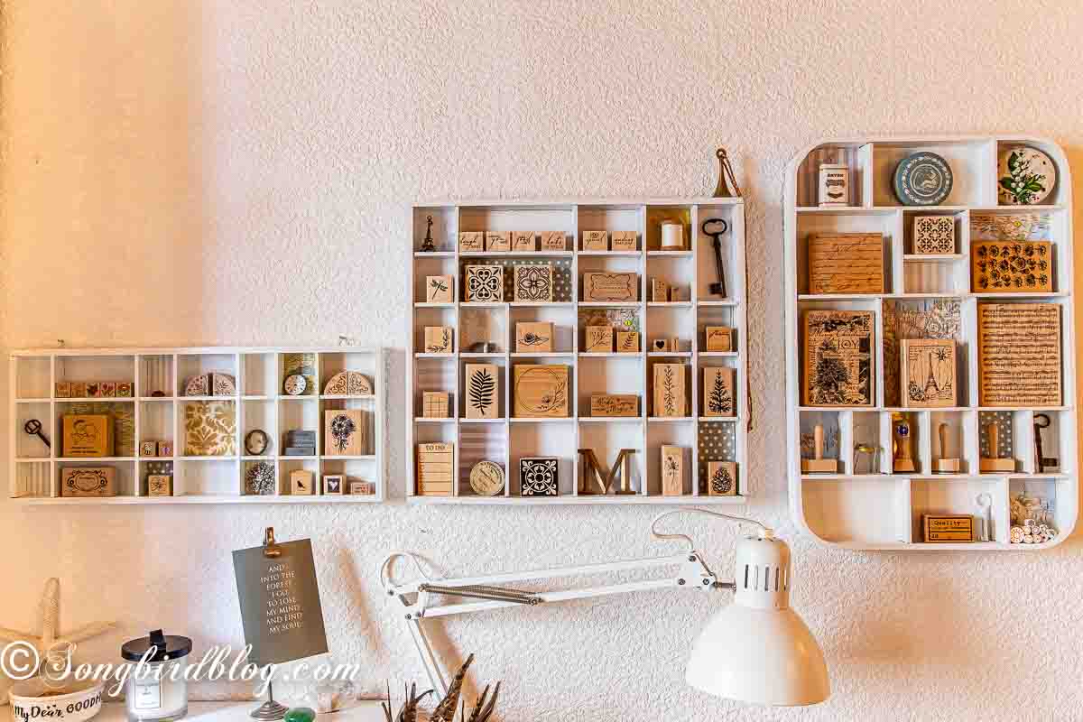 Wooden stamp storage using painted vintage printer’s trays mounted on a craft room wall for rubber stamp organisation.