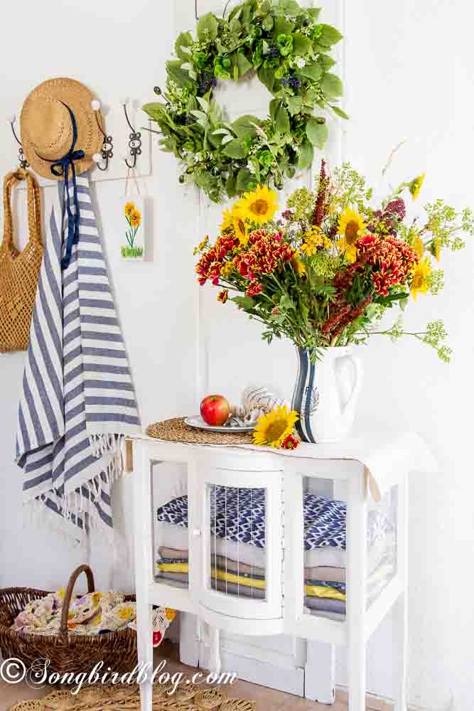 Easy vase painting idea: A white and navy striped pitcher vase filled with autumn-themed flowers, showcasing a rustic and artistic design.