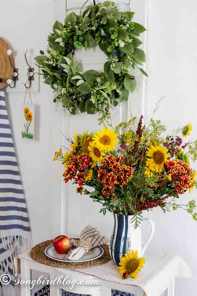 Hand painted vase with a rustic café design, paired with a bright bouquet of sunflowers and wildflowers for a cozy, artistic touch.