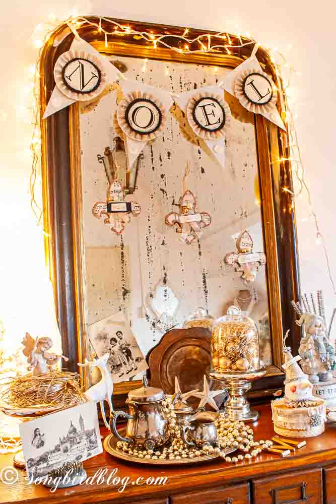 Vintage style Christmas vignette on a side table in front of a french mirror.