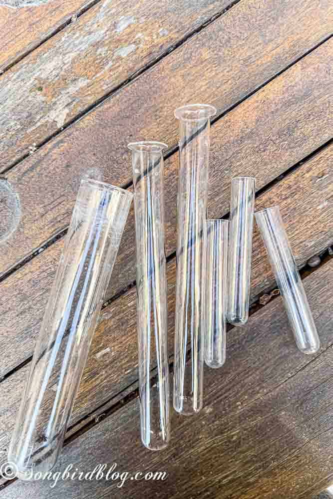 An assortment of glass tubes in different sizes on a wooden table.