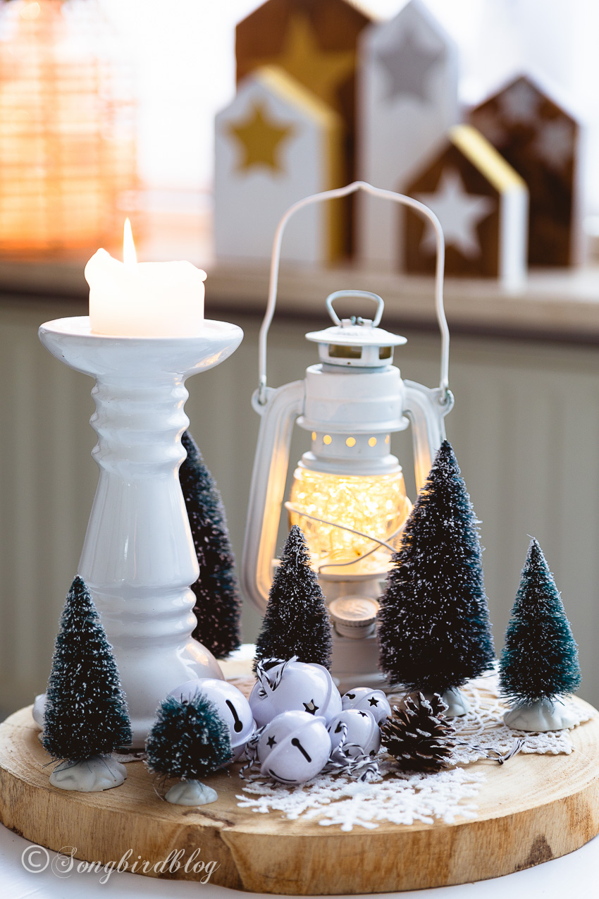 Wood slice Christmas vignette with faux snow, bottle brush trees, lantern and candle holder.